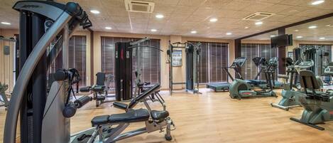 A gym with various exercise equipment, including treadmills and weight machines, and a wooden floor.