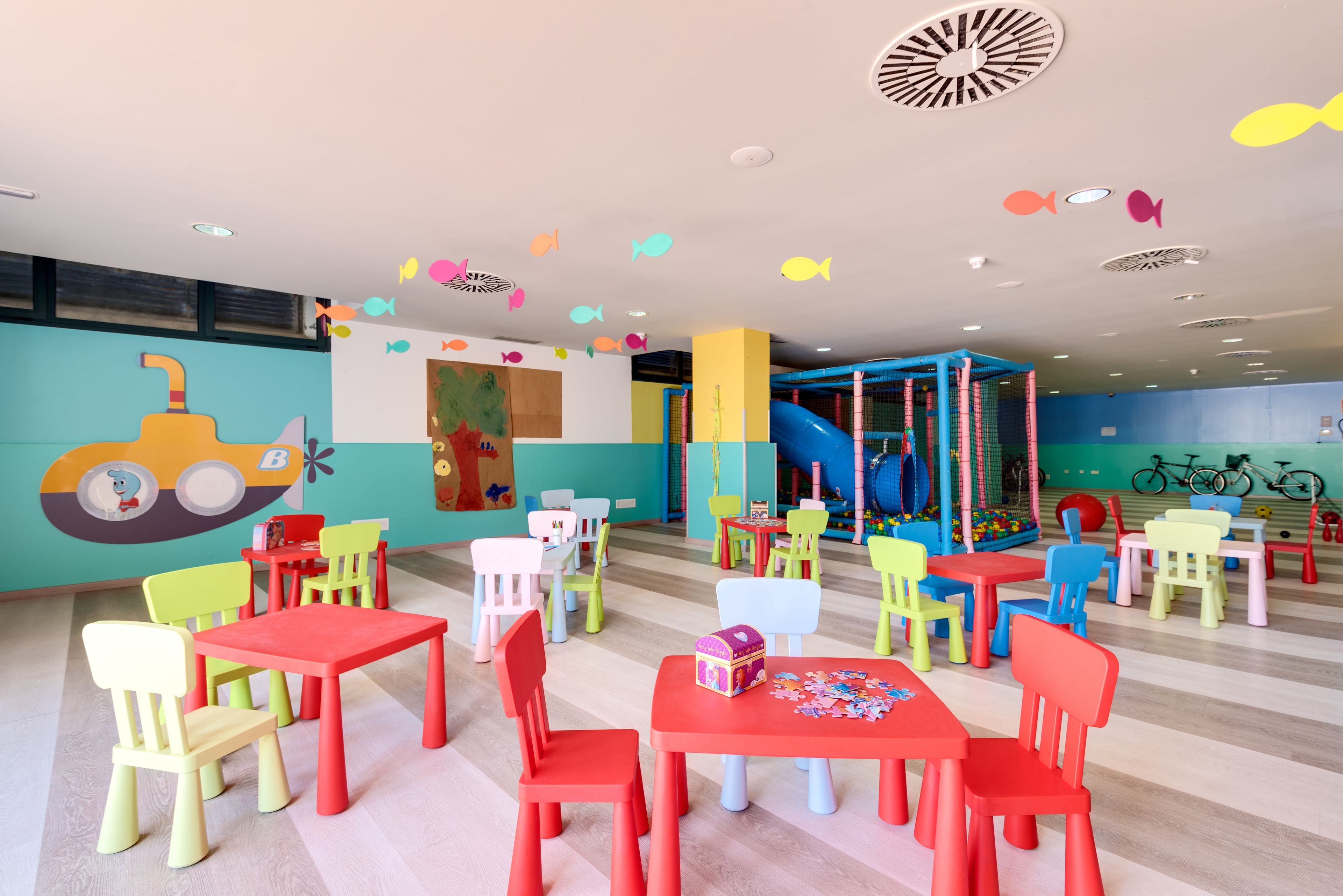 Zona de juegos infantiles con muebles de colores y un tobogán.
