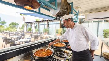 A chef preparing food in a kitchen with large pots and a view of outdoor seating.