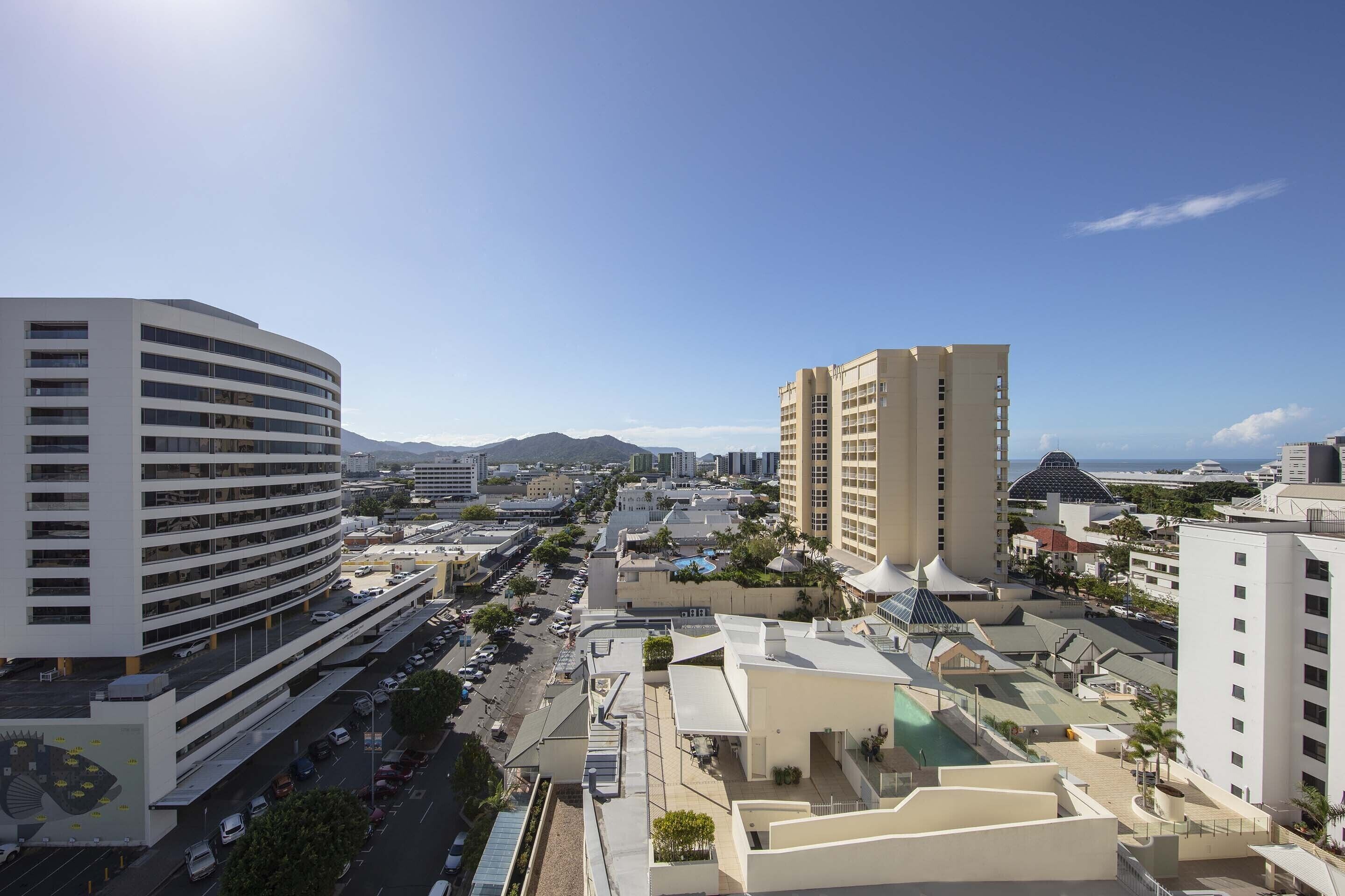 A modern urban area with high-rise buildings, a curved parking structure, and a clear view of the surrounding cityscape.