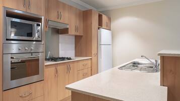 Una cocina moderna con armarios de madera, electrodomésticos de acero inoxidable y encimera blanca.