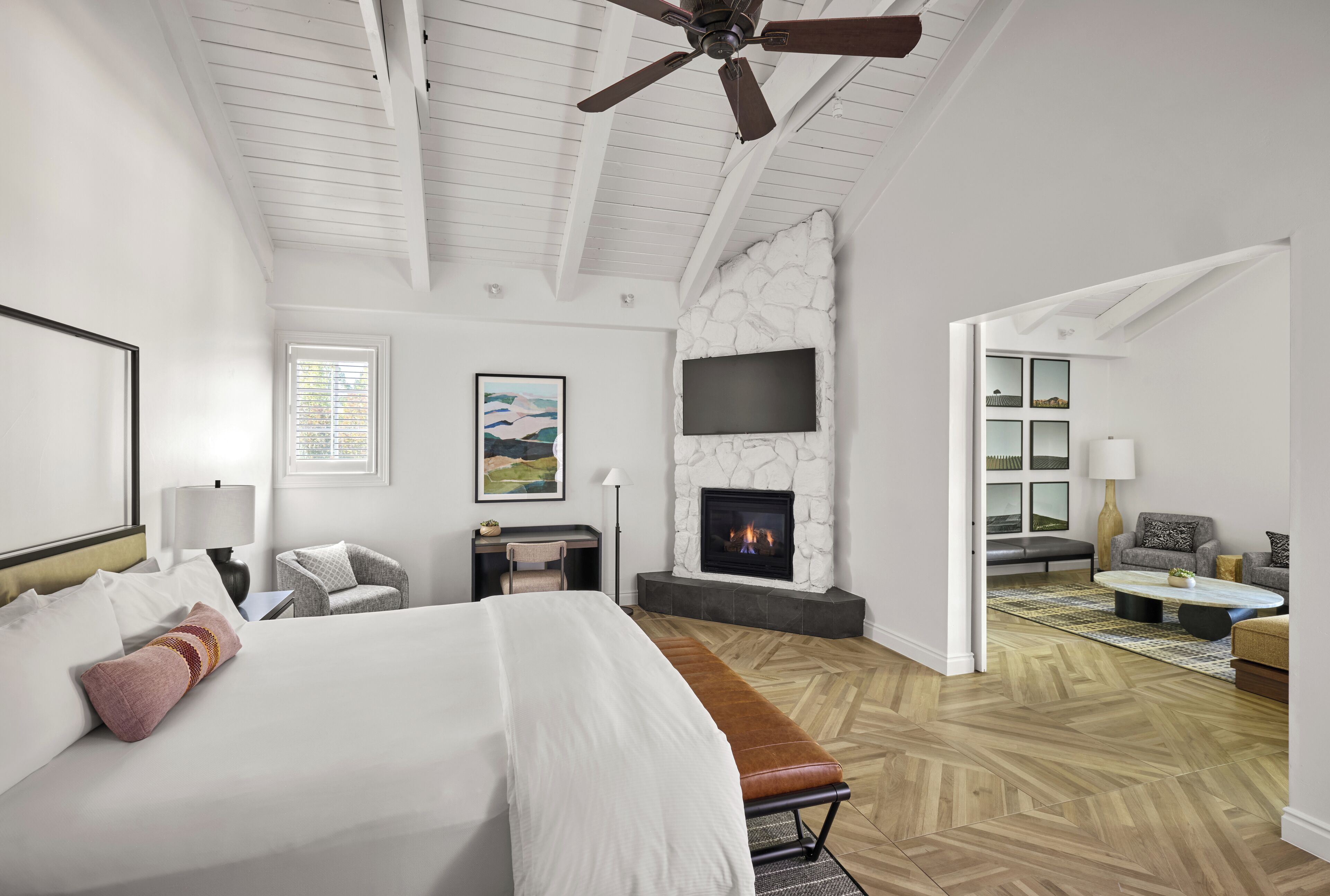 Une chambre d’hôtel moderne dotée d’un grand lit, d’une cheminée, d’un coin salon et d’un téléviseur fixé au mur.