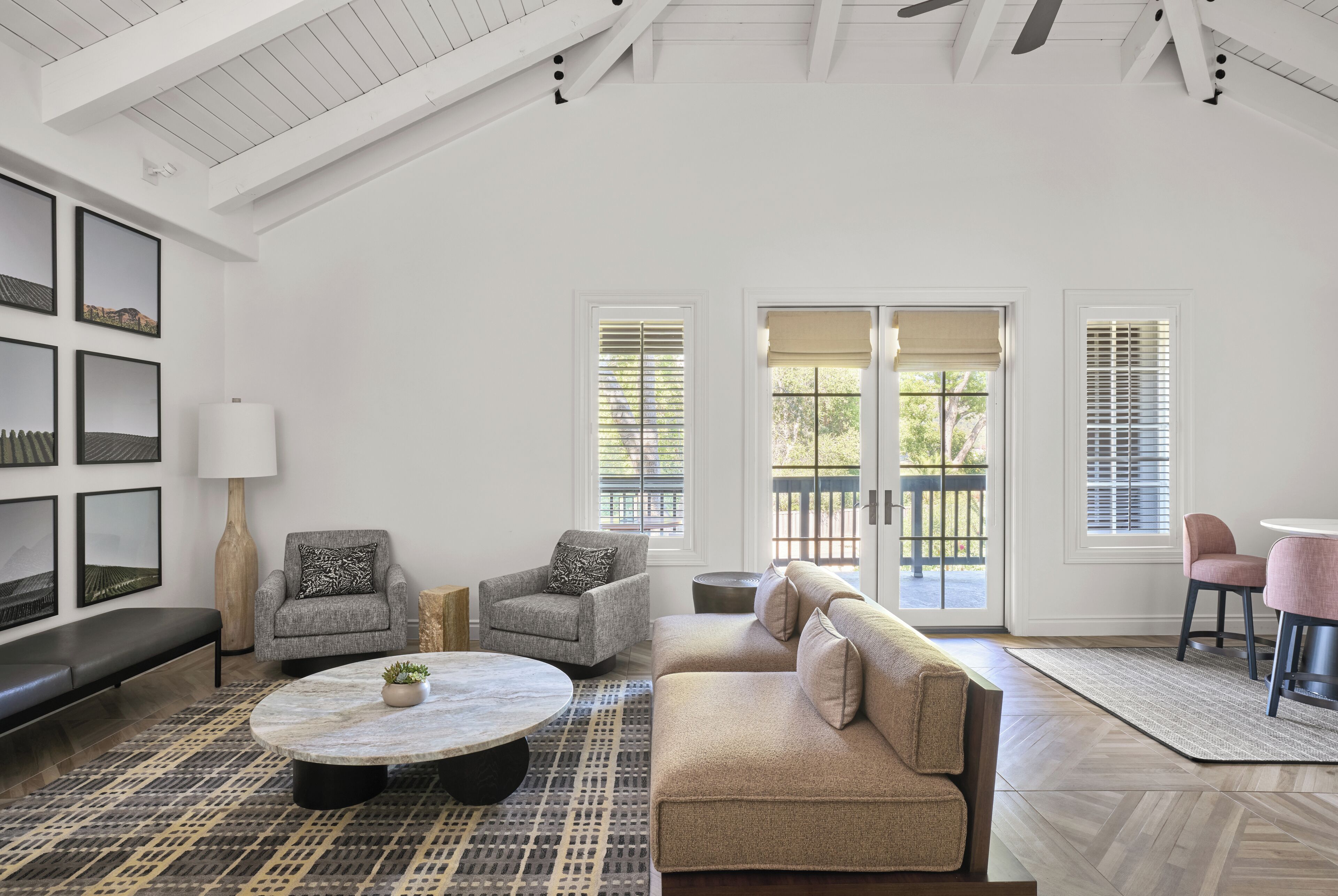 A spacious living room with a high ceiling, a sofa, armchairs, a coffee table, and a view through large windows.