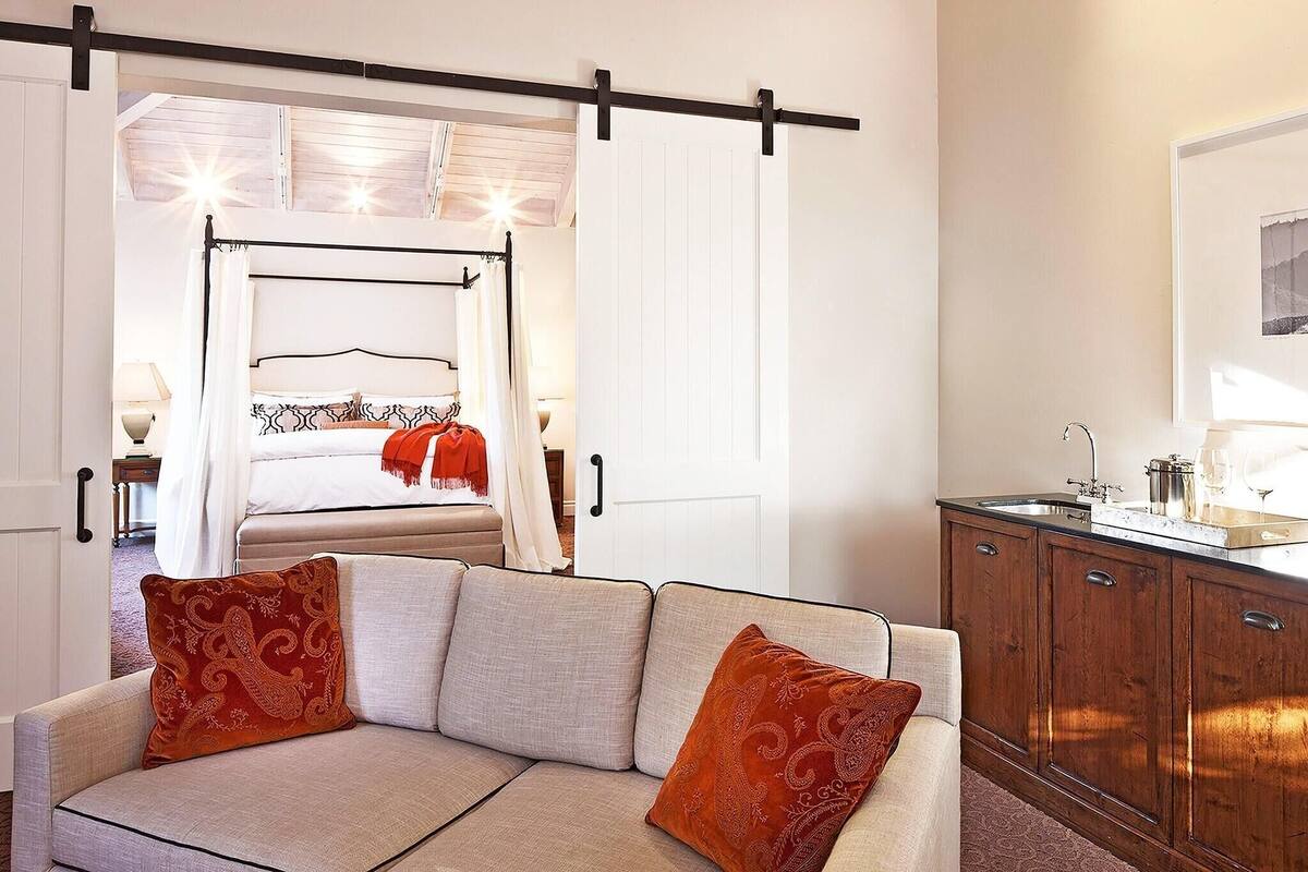 A hotel room with a bed, a sofa, a cabinet, and a window.