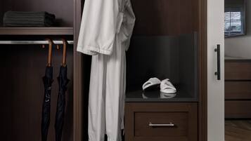 Un armario de madera con espejo, una barra para colgar ropa y un estante con ropa doblada y zapatos.