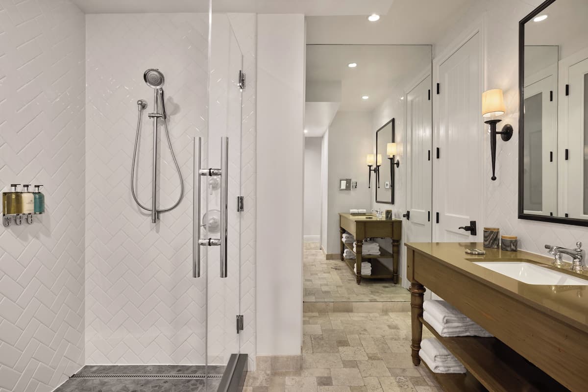 A modern bathroom with a glass-enclosed shower, a wooden vanity with a sink, and a large mirror.