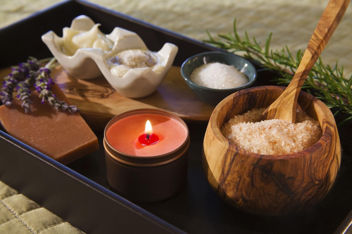 A tray with a lit candle, a wooden bowl of salt, a small bowl of sugar, and a bar of soap.