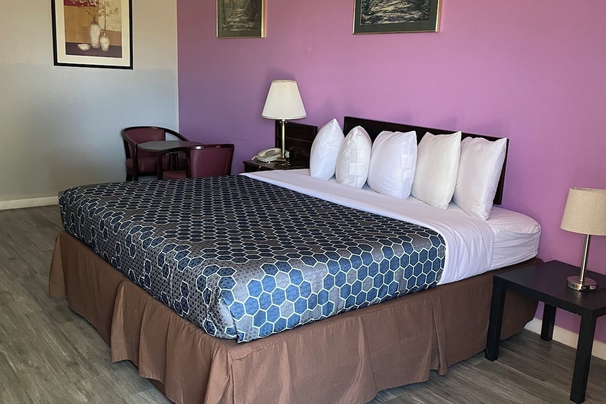 Habitación de hotel con una cama grande, un escritorio, una silla y dos cuadros en la pared.