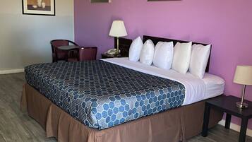 Ein Hotelzimmer mit einem großen Bett, einem Schreibtisch, einem Stuhl und zwei Bildern an der Wand.