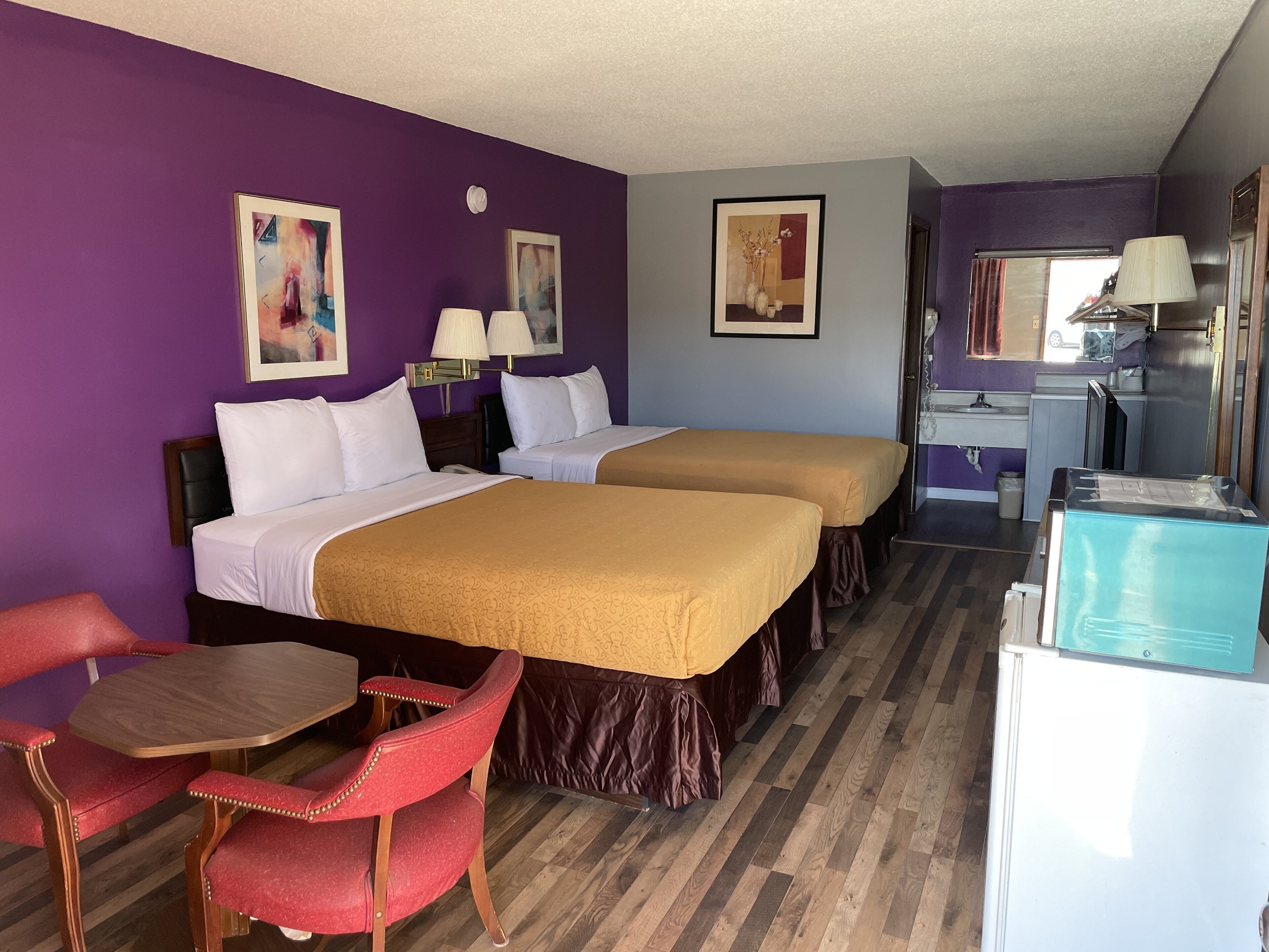 Une chambre d’hôtel avec deux lits, un bureau, une chaise et une kitchenette.