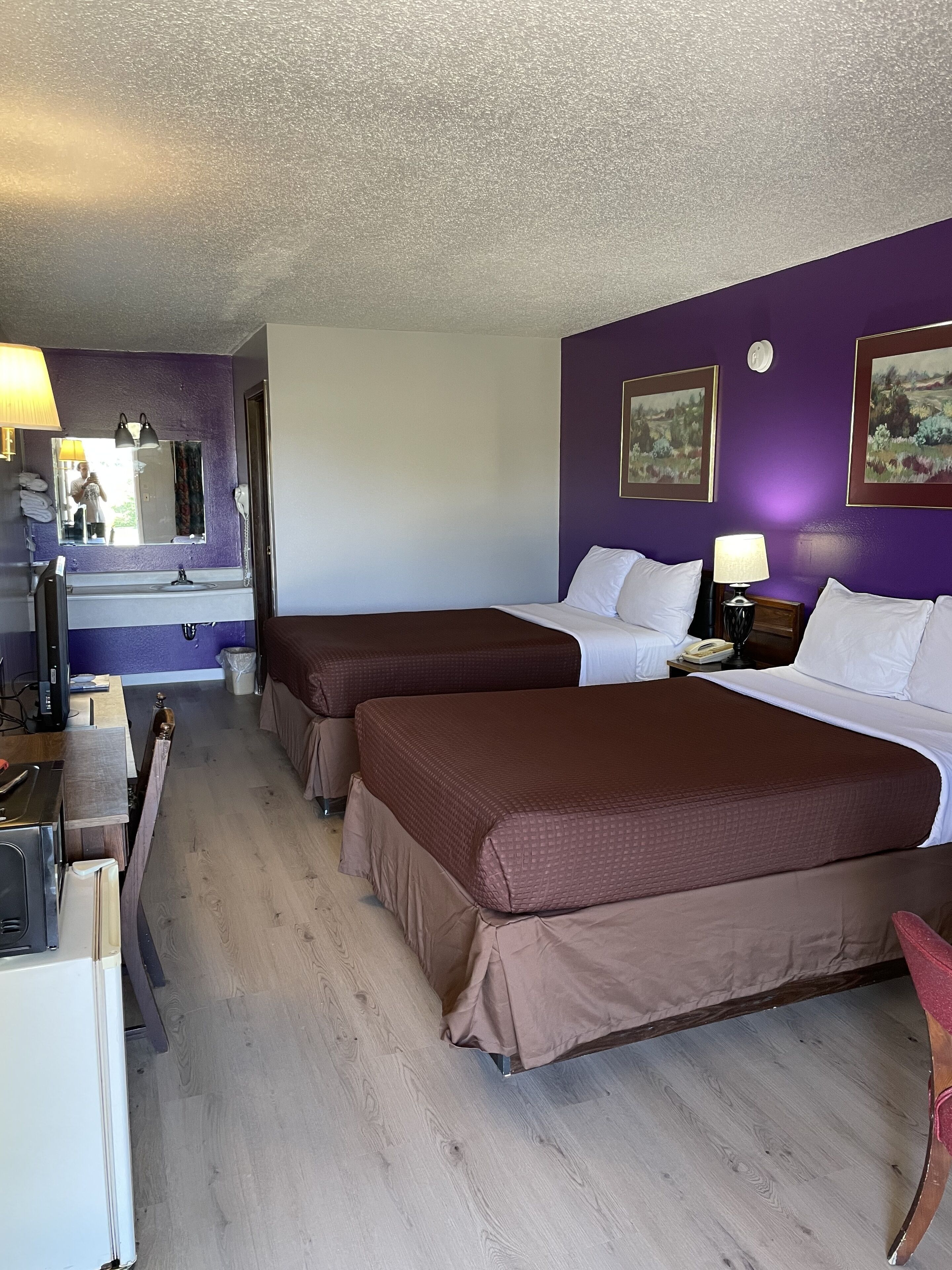 Habitación de hotel con dos camas, un baño y un escritorio con computadora.