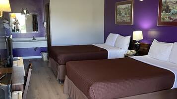 Habitación de hotel con dos camas, un baño y un escritorio con computadora.