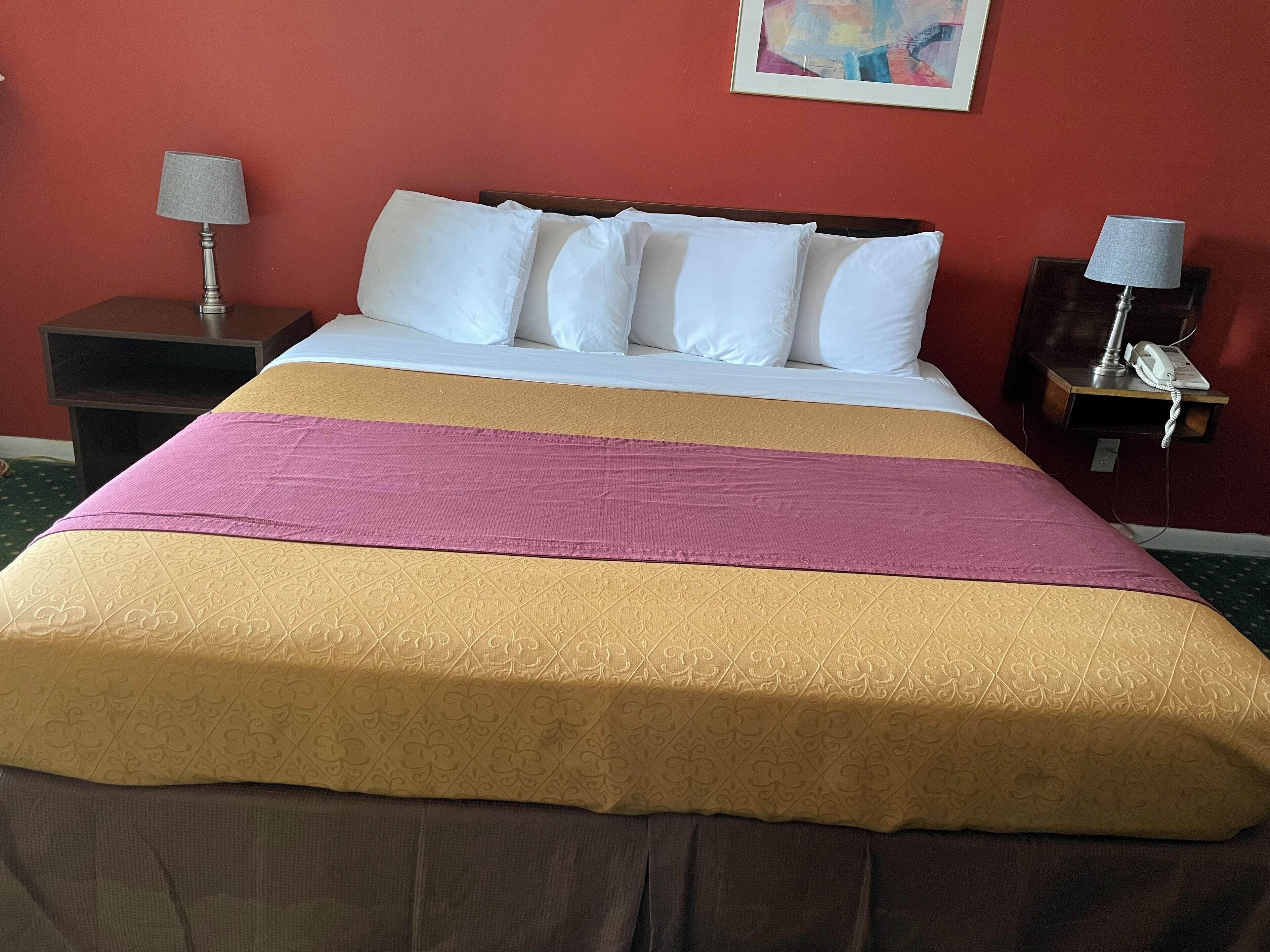 A hotel room with a bed, two nightstands, and a painting on the wall.