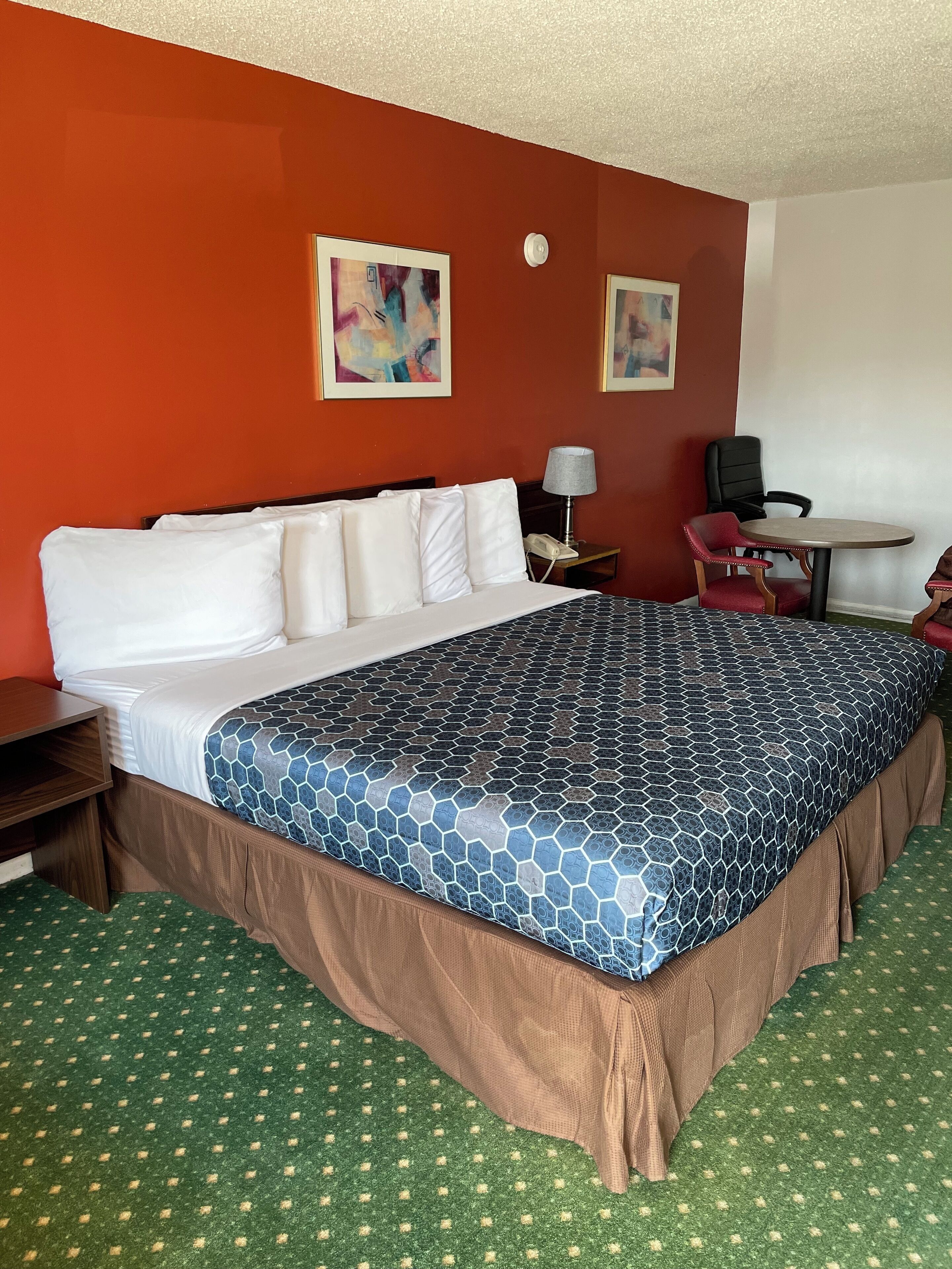 Une chambre d’hôtel avec un grand lit, un bureau avec une lampe et deux chaises.
