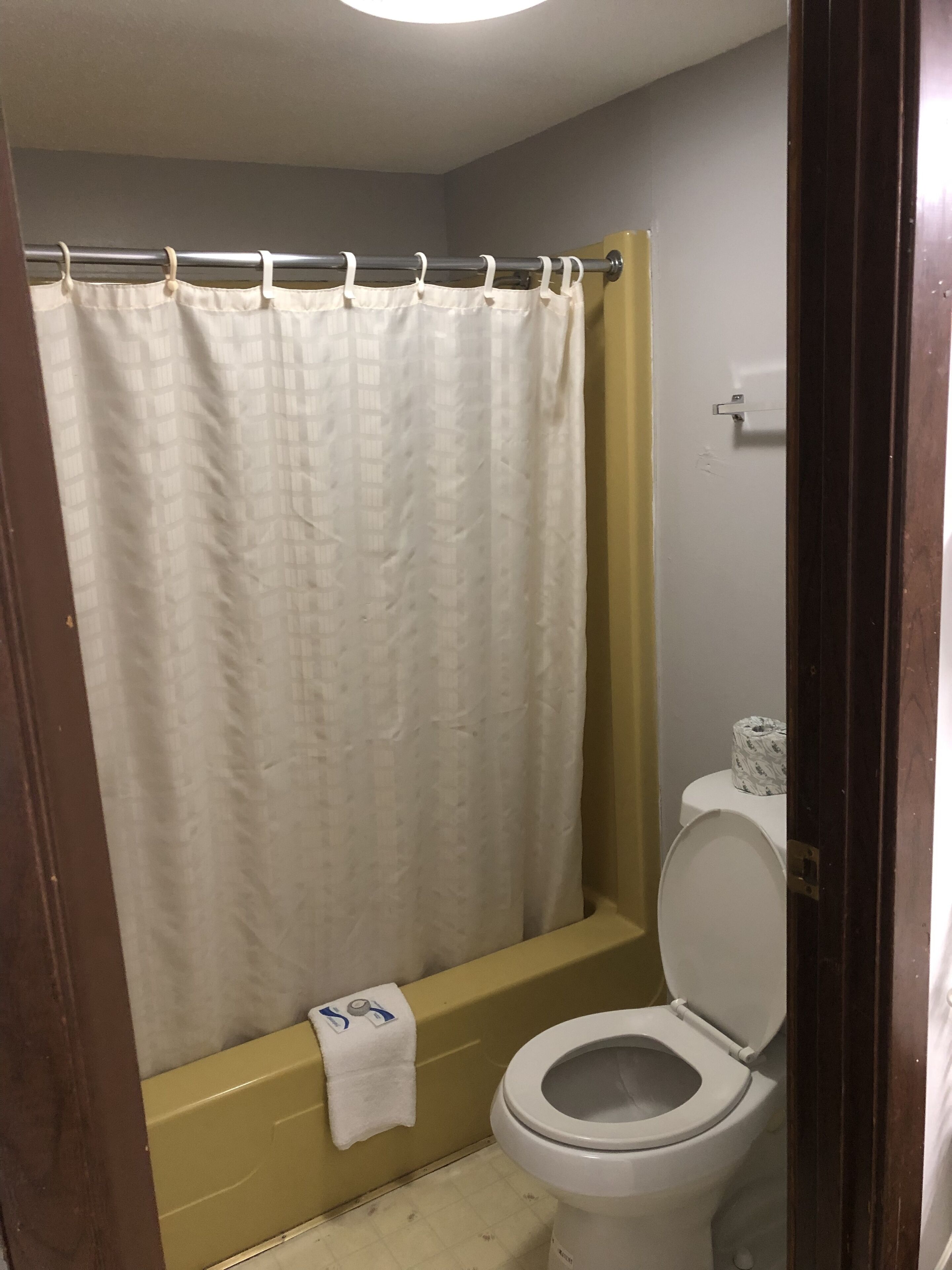 Un baño con cortina de ducha, bañera y retrete.