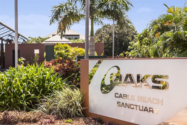 Un panneau indiquant l’entrée du sanctuaire de Cable Beach, avec un design moderne et une végétation luxuriante environnante.
