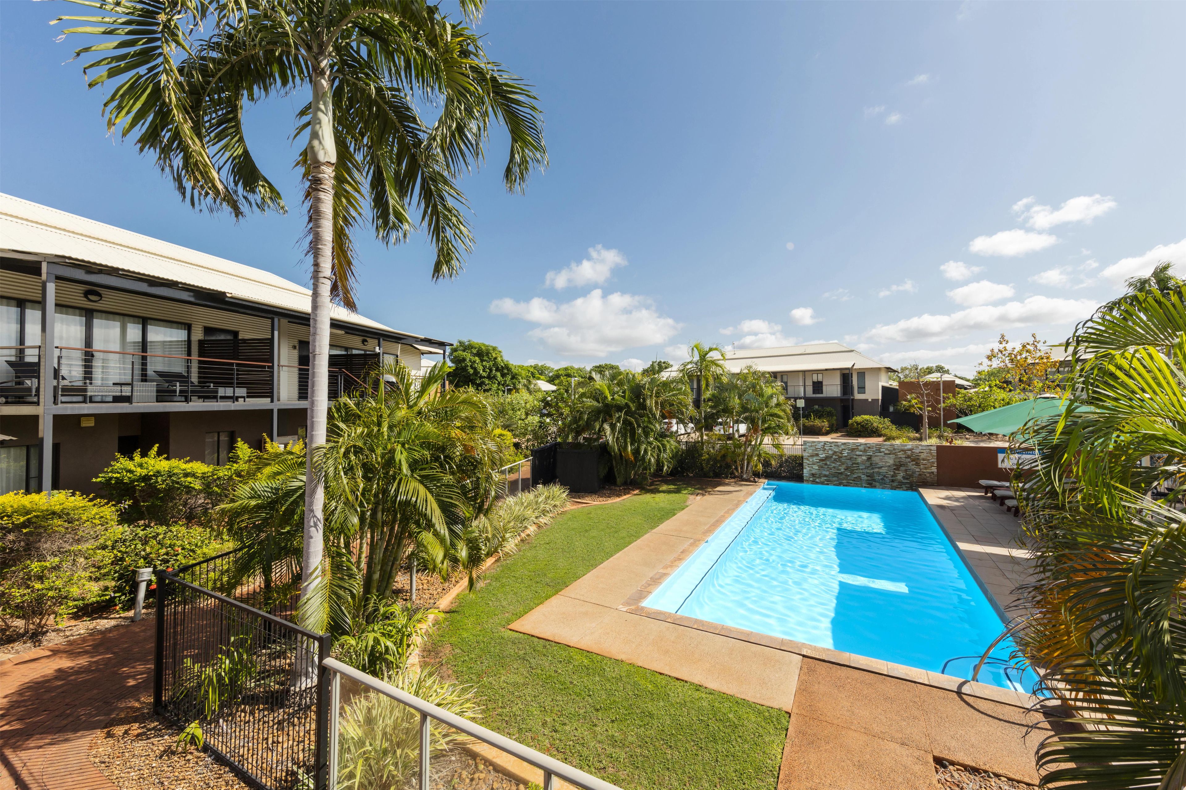 Un barrio residencial con piscina, palmeras y casas modernas.