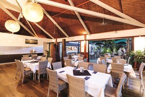 Un restaurante con techos altos, muebles de mimbre y vistas al área exterior.