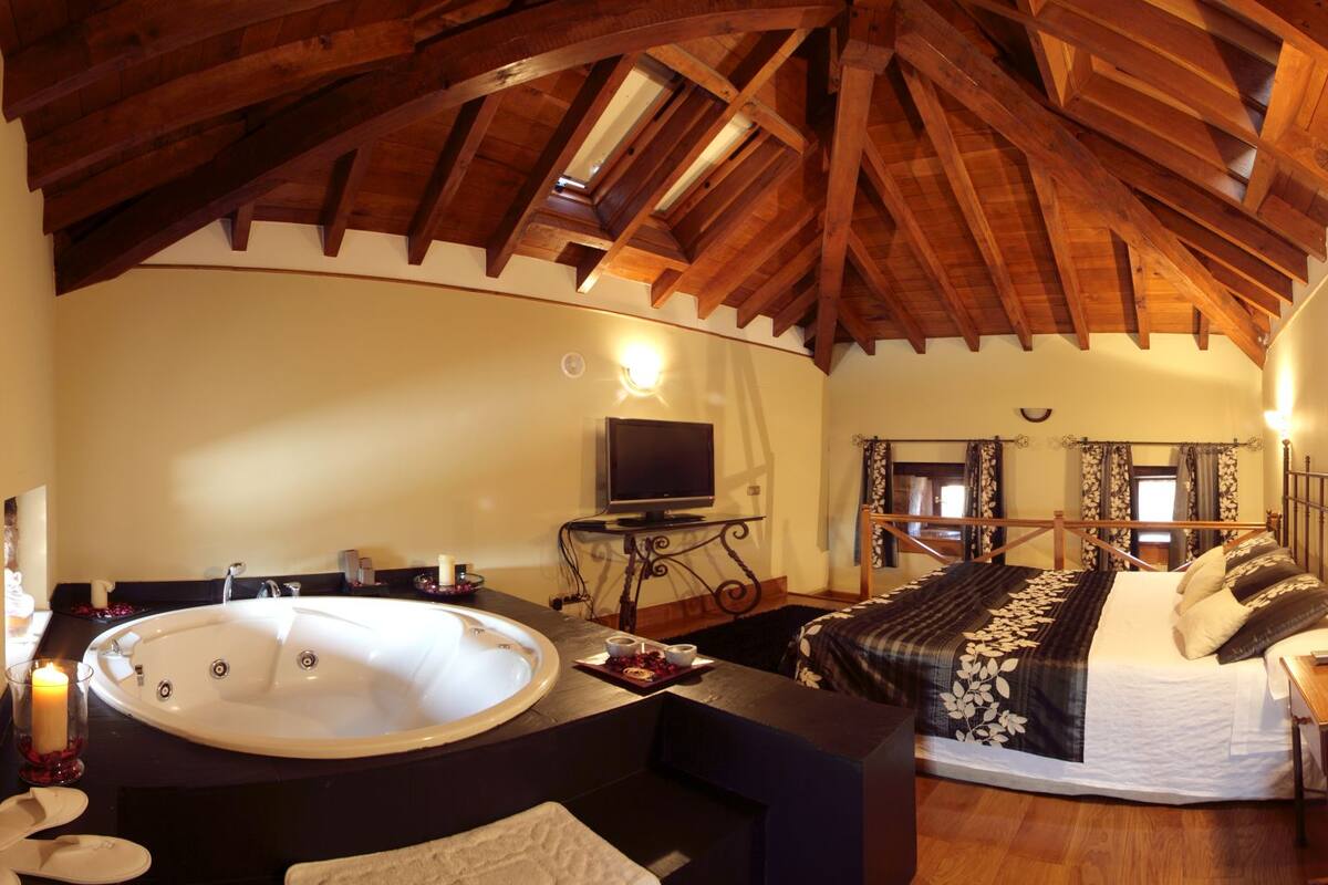 Um quarto aconchegante com uma cama grande, um espaço de estar com televisão e uma banheira.