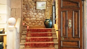 A staircase with red carpeted steps leading to a wooden door. - Palacio Guevara (Valdaliga)