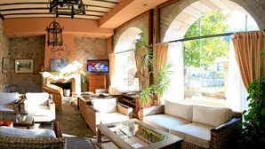 A cozy lounge area with wicker furniture, a fireplace, and a TV. - Palacio Guevara (Valdaliga)