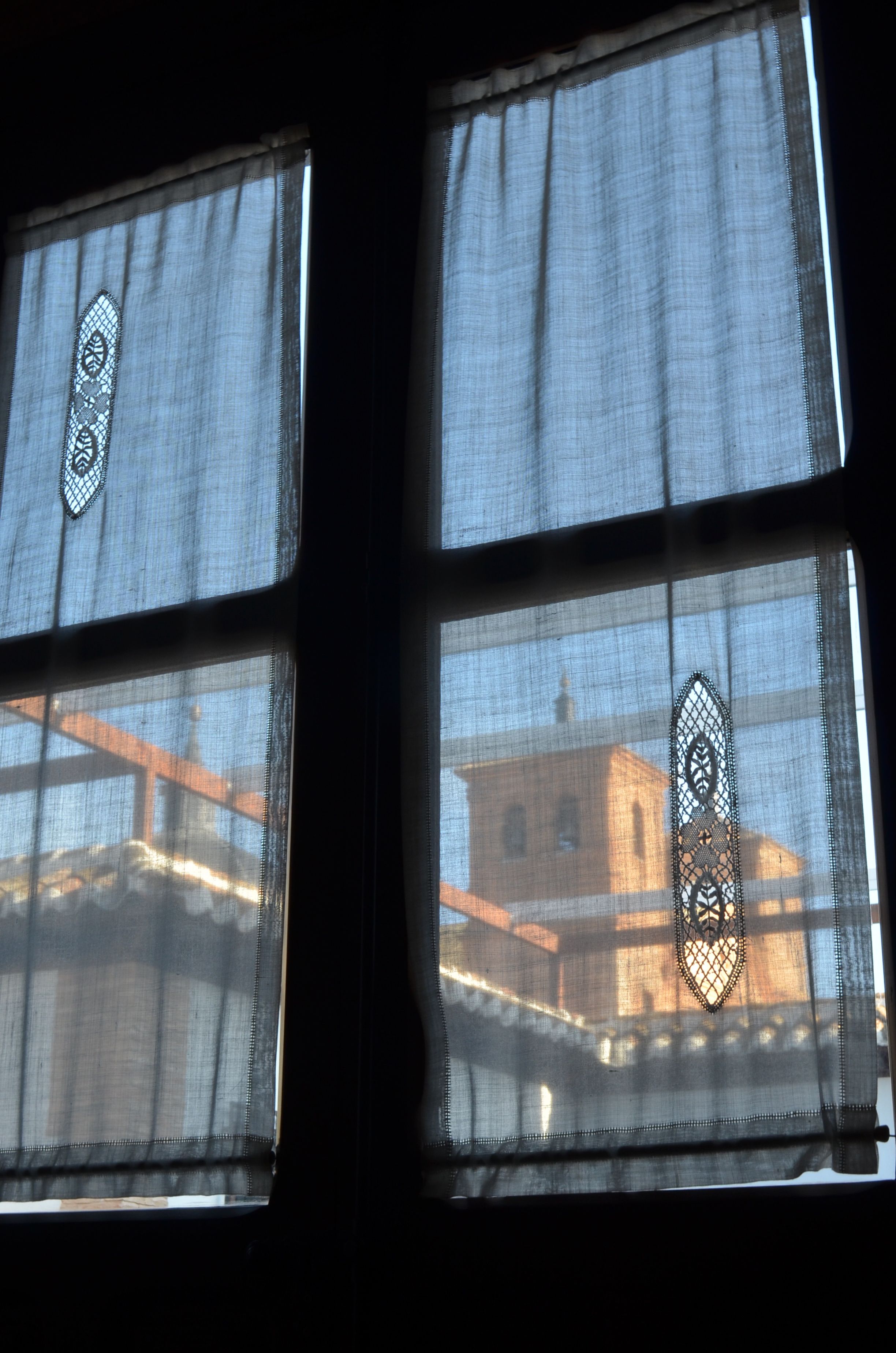 Una ventana con cortina estampada y vista a un edificio con cúpula.