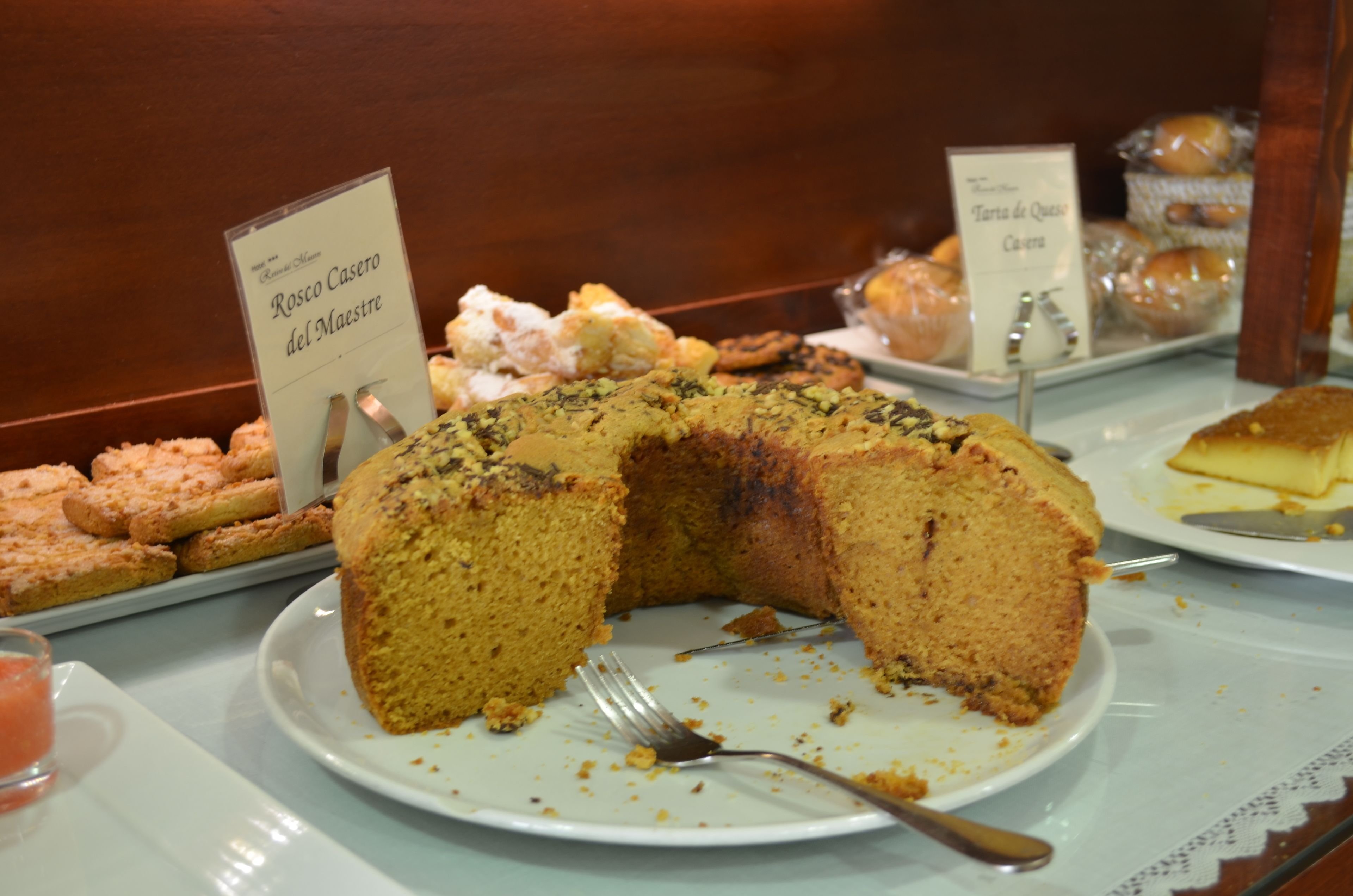 A display of various baked goods including a large cake with a label reading "Rosco Casero del Maestro".