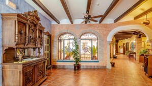 A spacious lobby with a high ceiling, a wooden reception desk, and a large window with a view of the outside. - Hospedium Hotel Retiro del Maestre (Almagro)