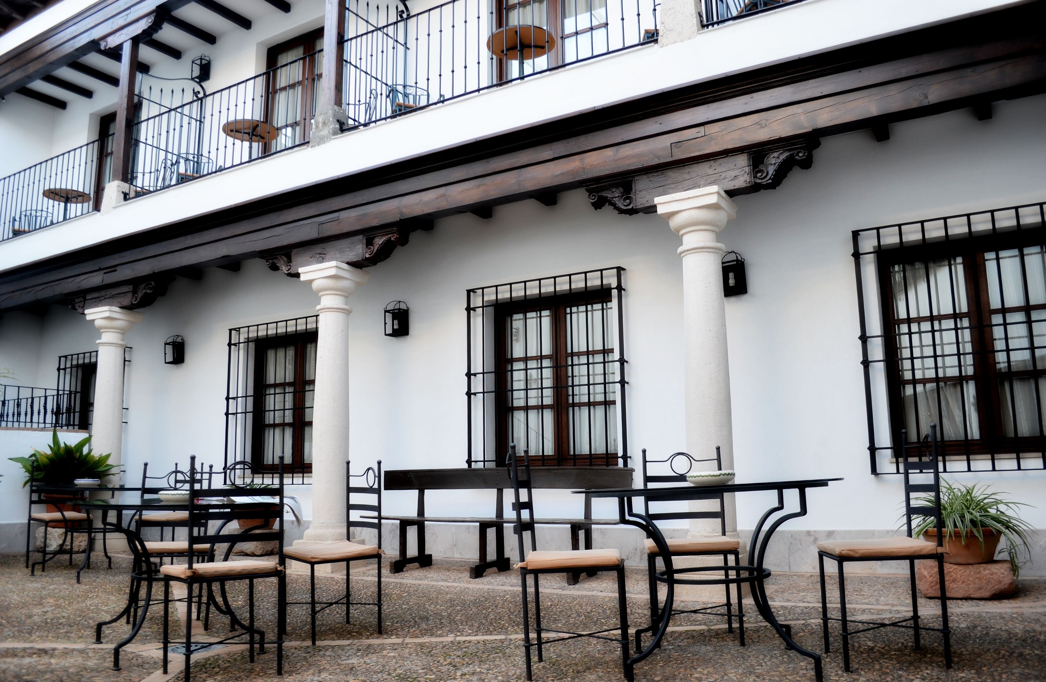 Un edificio con terraza al aire libre, paredes blancas y barandillas de metal negro.