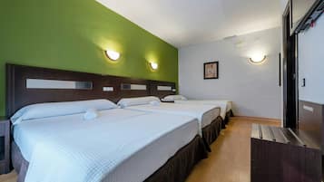 Habitación de hotel con dos camas, suelo de madera y pared verde.