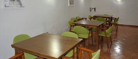 Un salón de conferencias con mesas y sillas, luminarias en las paredes y obras de arte decorando las paredes.