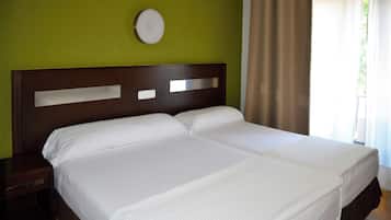 Una cama doble con cabecera de madera, una mesita de noche y un espejo redondo fijado a la pared.