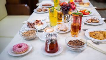 A breakfast buffet with various dishes, drinks, and condiments.
