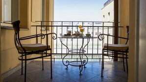 A balcony with two chairs and a table, overlooking a building. - Hotel Liberty (Prague)