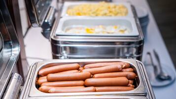 Ein Buffet mit verschiedenen Speisen, darunter Hotdogs, Speck und weitere Gerichte.