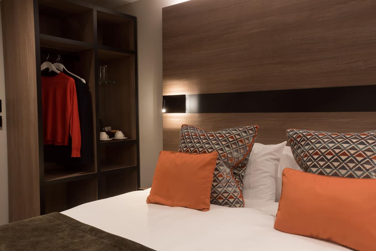 A bedroom with a bed, a wardrobe, and a nightstand.