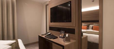 Ein Hotelzimmer mit Holzschreibtisch, Flachbildfernseher, Telefon, Notizblock und Taschentuchbox.