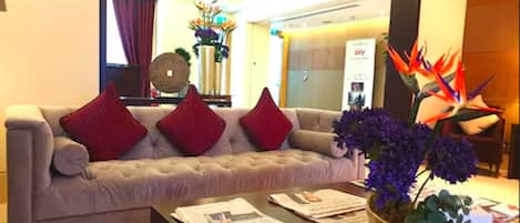Una sala de estar moderna con un sofá gris, cojines rojos y una mesa de centro con revistas.