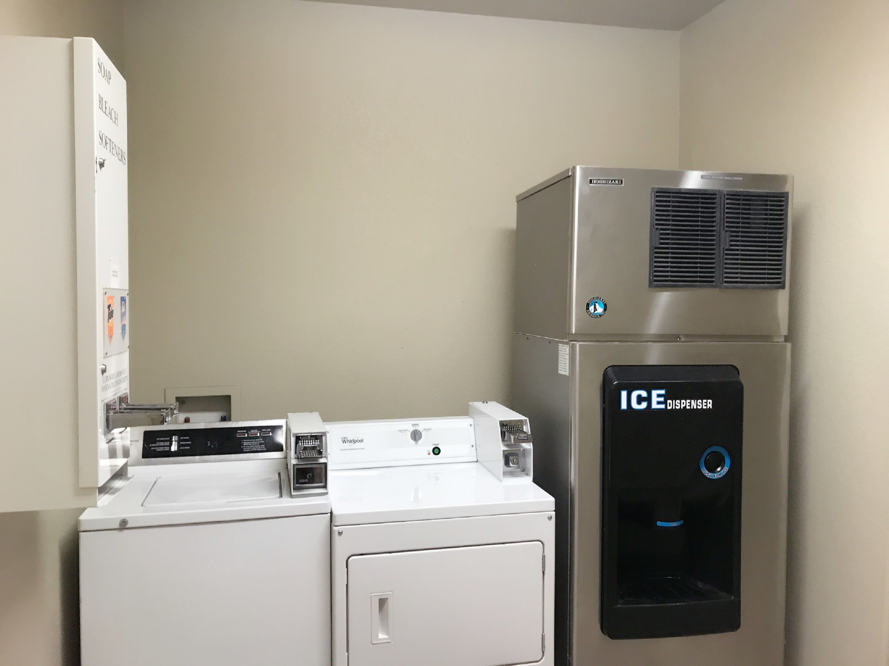 Un área de lavandería con una lavadora Whirlpool, un refrigerador Bosch y dispensador de hielo.