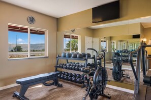 A gym with a bench, dumbbells, and exercise equipment.