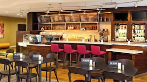 Un restaurante con zona de bar, diversas opciones de asientos y una vitrina con la carta.