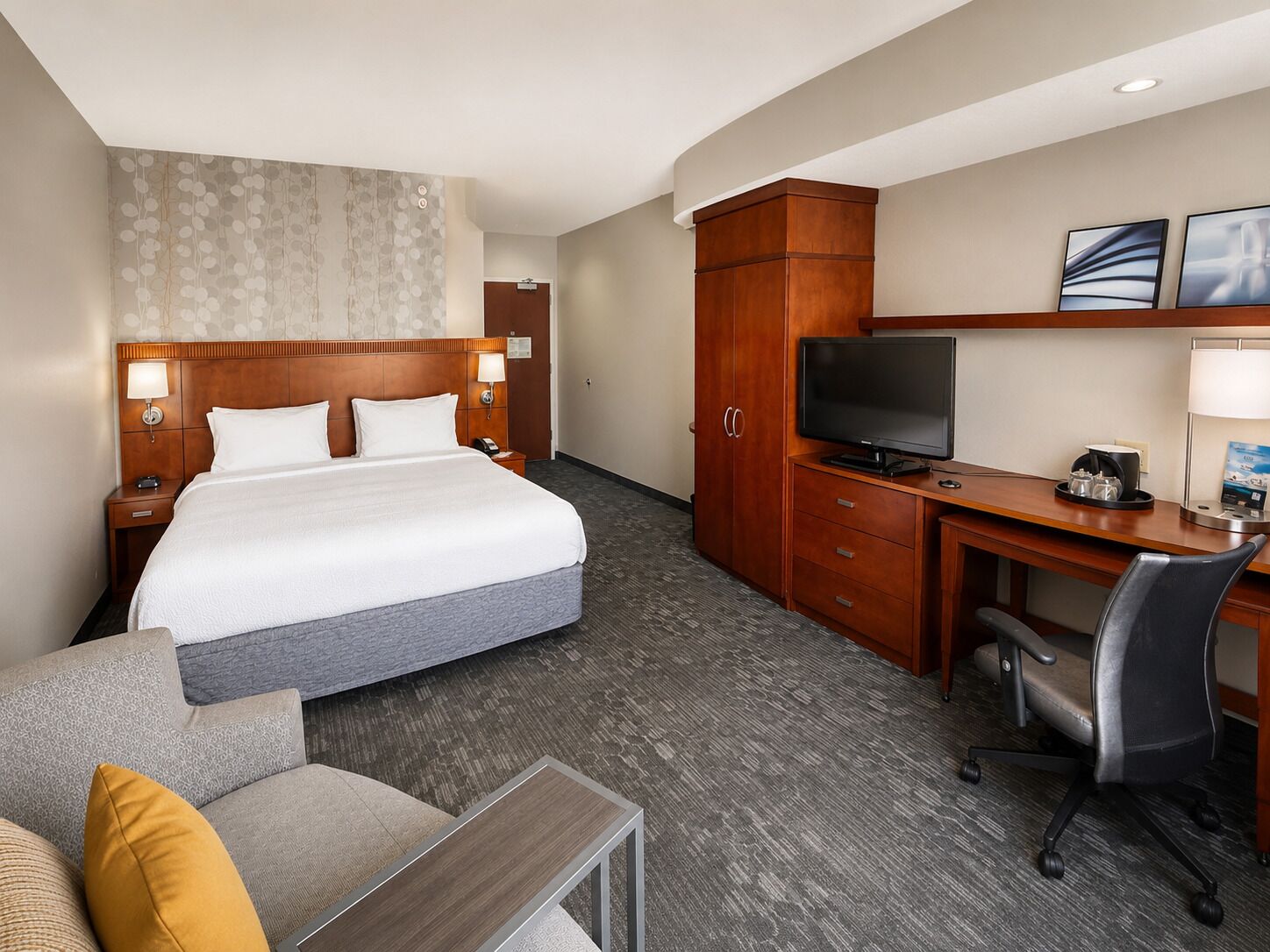 Una habitación de hotel con cama, escritorio, televisor y zona de estar.