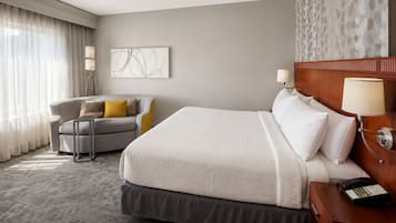 Habitación de hotel con una cama grande, un sofá, un escritorio con teléfono y una pared con diseño decorativo.