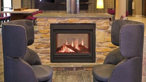 Una chimenea con revestimiento de piedra, dos sillones tapizados con estampado de estrella y un interior moderno con un televisor de pantalla plana sobre la chimenea.