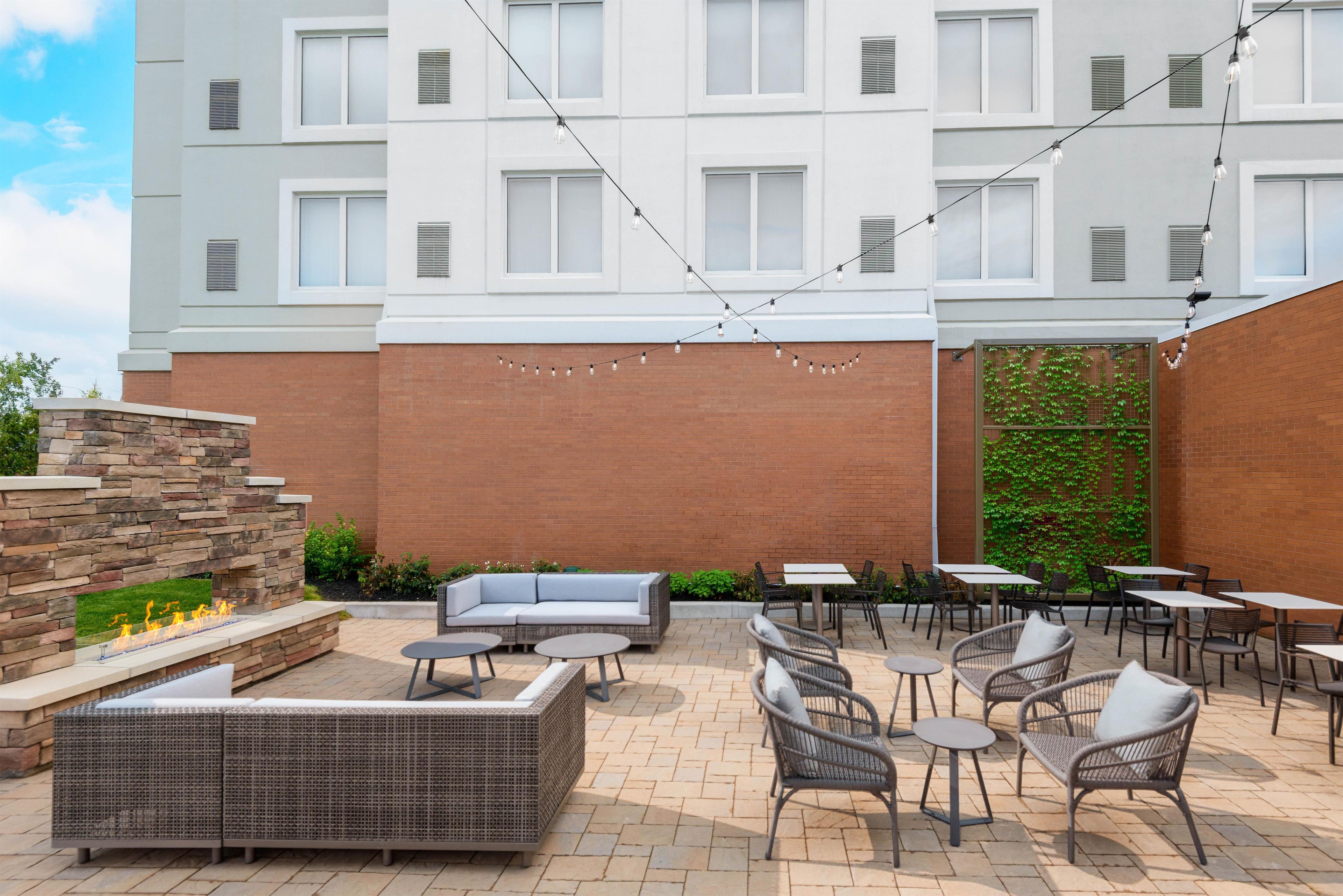 Un espace extérieur aménagé en terrasse, avec un foyer en pierre, des sièges et des tables.