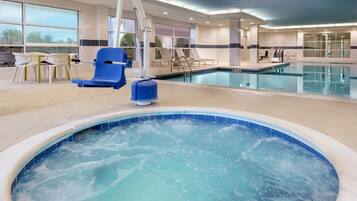 Piscina interna com banheira de hidromassagem, espreguiçadeiras e um solário.