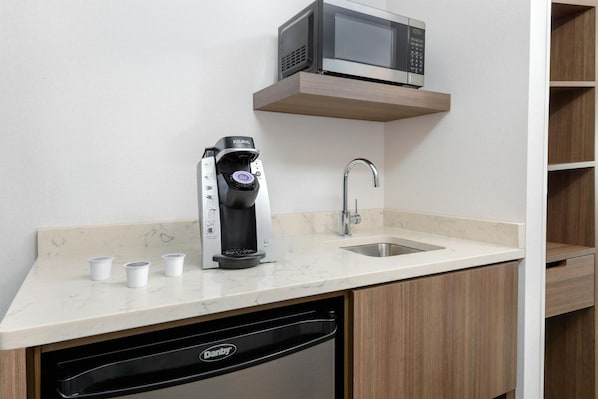 Cocina compacta equipada con cafetera, microondas y lavabo.