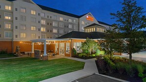 Een Hilton Garden Inn hotel met een goed verlichte ingang, een terras en een aangelegde tuin.