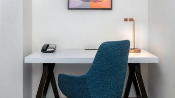 Una sedia d'ufficio moderna con base metallica, una scrivania con il telefono e una lampada da terra.