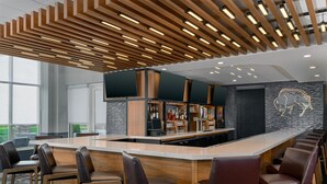 Een moderne bar met een lange toonbank, diverse zitmogelijkheden en een opvallend plafondontwerp.